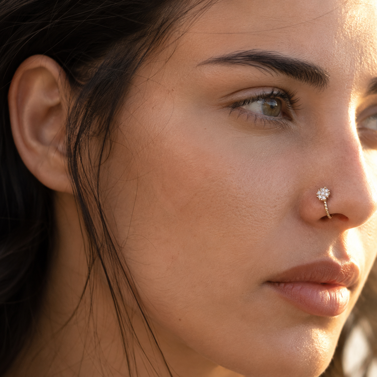 Gros plan sur un faux piercing nez doré avec breloque en forme d'étoile pavée de strass, porté sans trou sur l'aile du nez