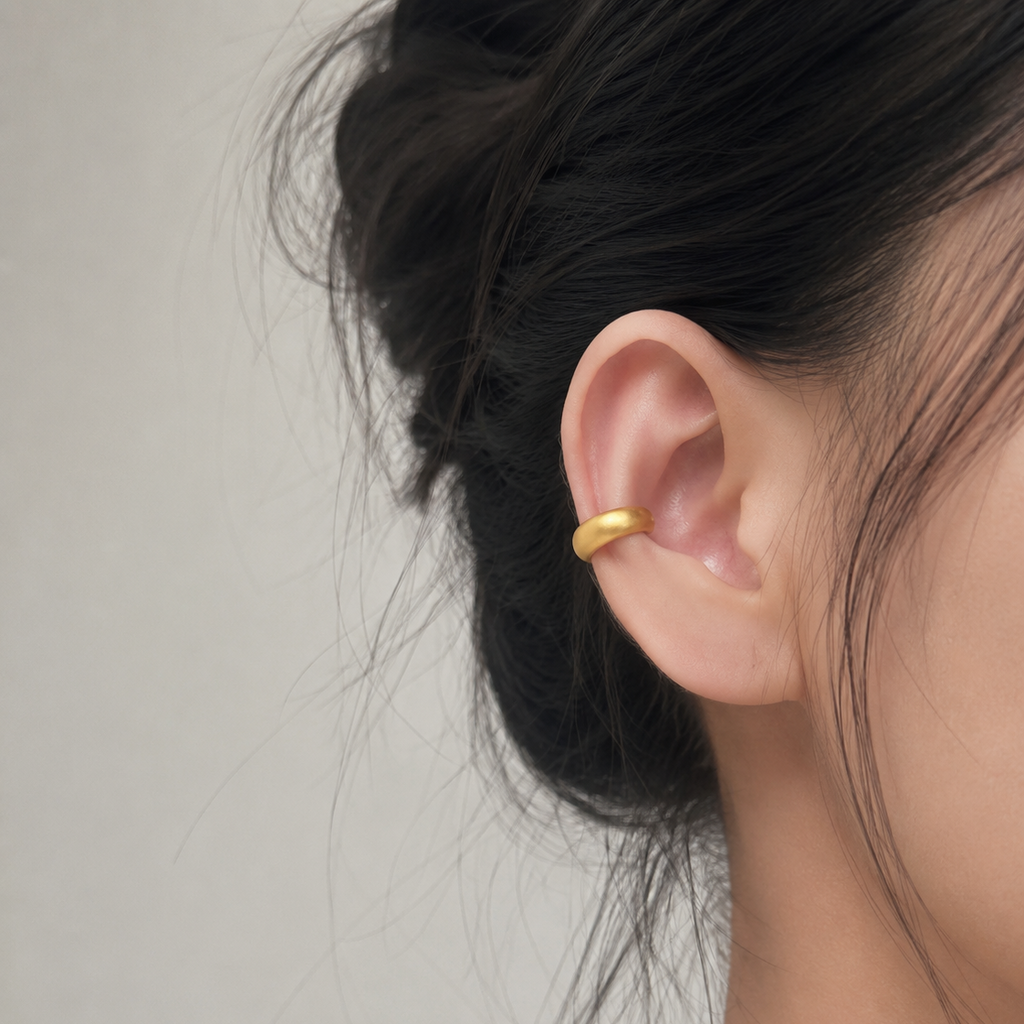 Ear cuff bombé minimaliste porté au creux de la conque, chignon tressé
